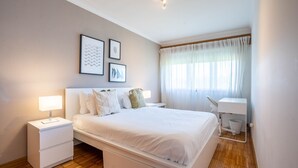 A modern bedroom with a large bed, bedside tables, a desk, and a chair. - Infante Cozy 1BR w/ Parking by LovelyStay (Vila Nova de Gaia)