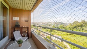 A balcony with a view of a green landscape, a wooden wall, and a metal fence. - Infante Cozy 1BR w/ Parking by LovelyStay (Vila Nova de Gaia)