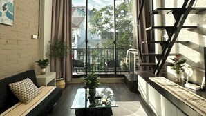 Una sala de estar moderna con un ventanal grande, un sofá, una mesa de centro y una escalera.