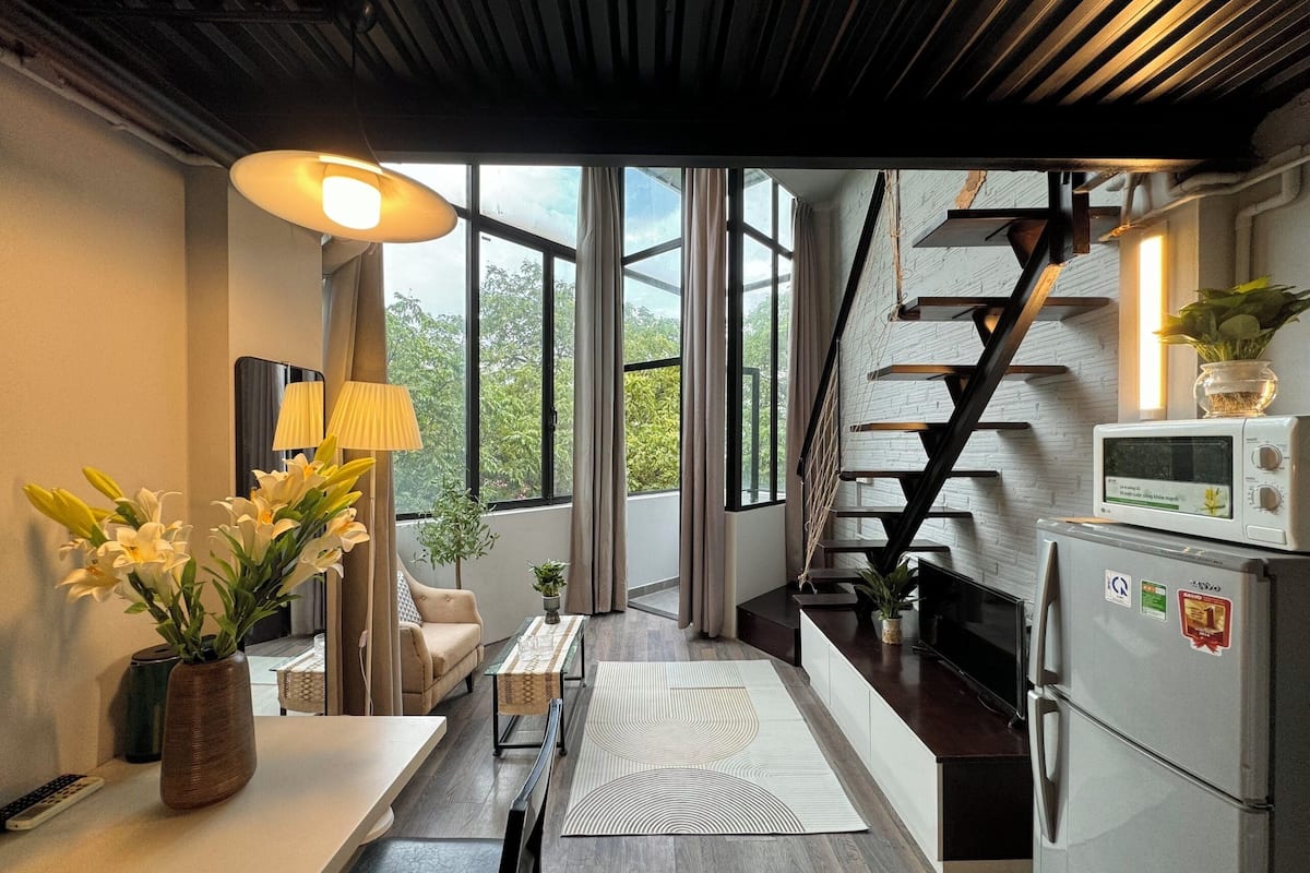 A modern kitchen with a built-in microwave, a refrigerator, and a staircase leading to an upper level.