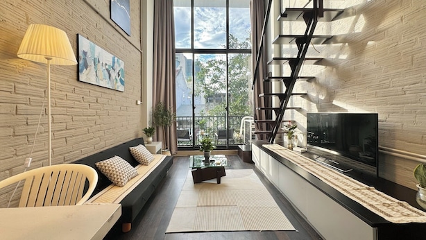 Una sala de estar moderna con un sofá, una mesa de centro, un televisor y una escalera.