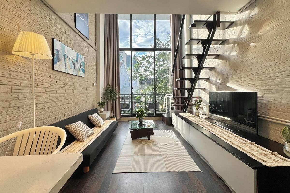 A modern living room with a sofa, a coffee table, a TV, and a staircase.