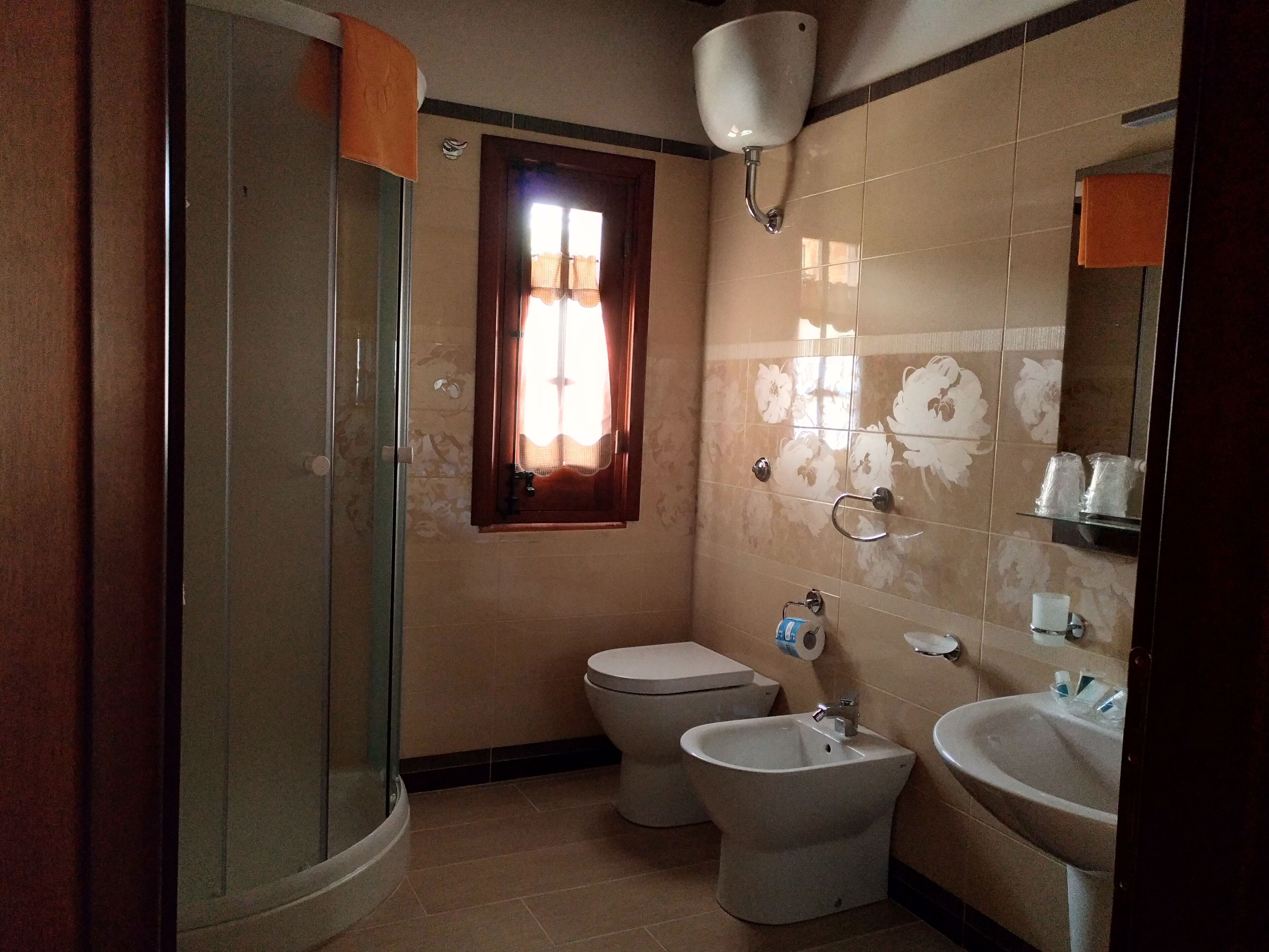 A bathroom with a glass-enclosed shower, a toilet, and a sink.