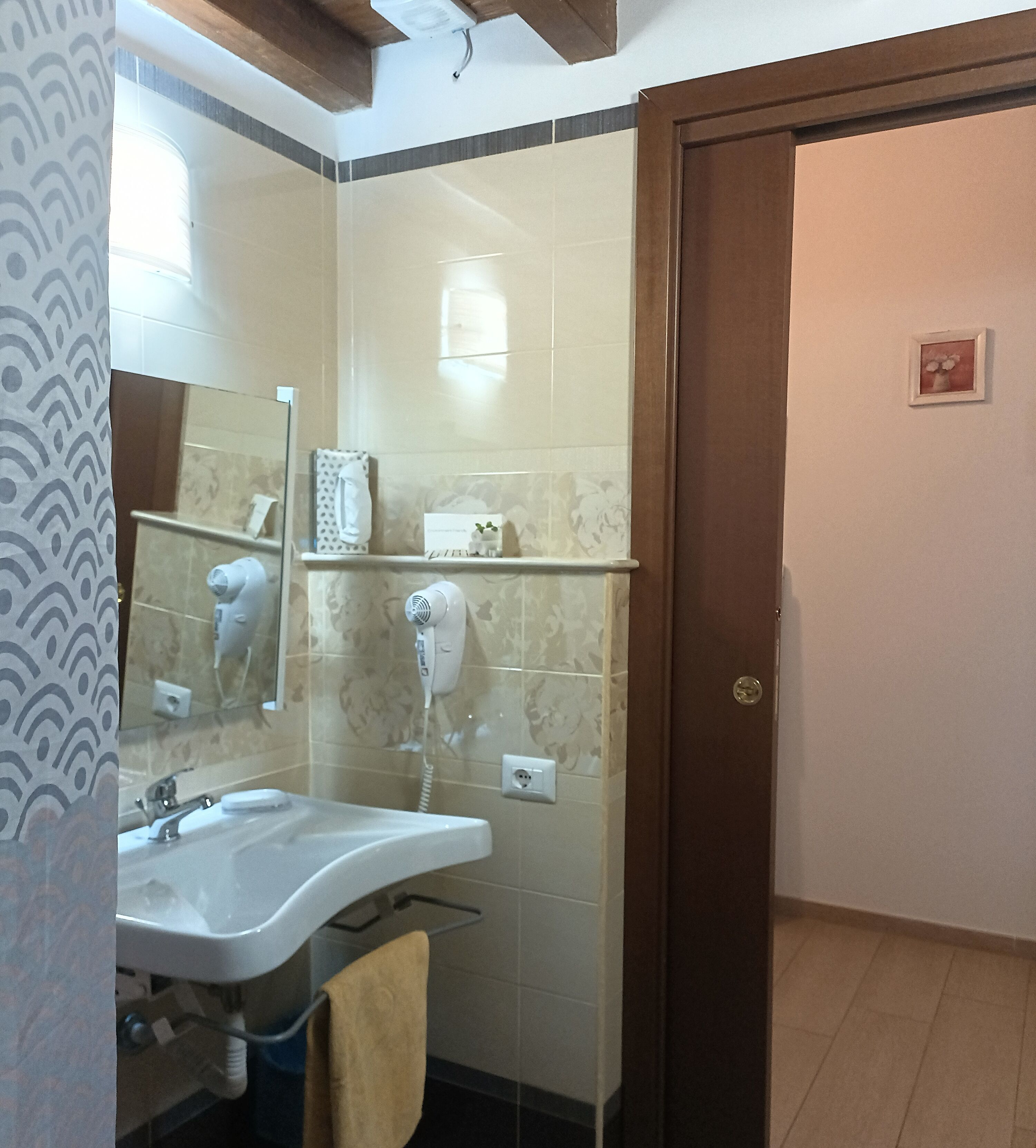 A bathroom with a sink, mirror, towel rack, and a hairdryer on the wall.