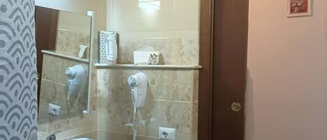 A bathroom with a sink, mirror, towel rack, and a hairdryer on the wall.
