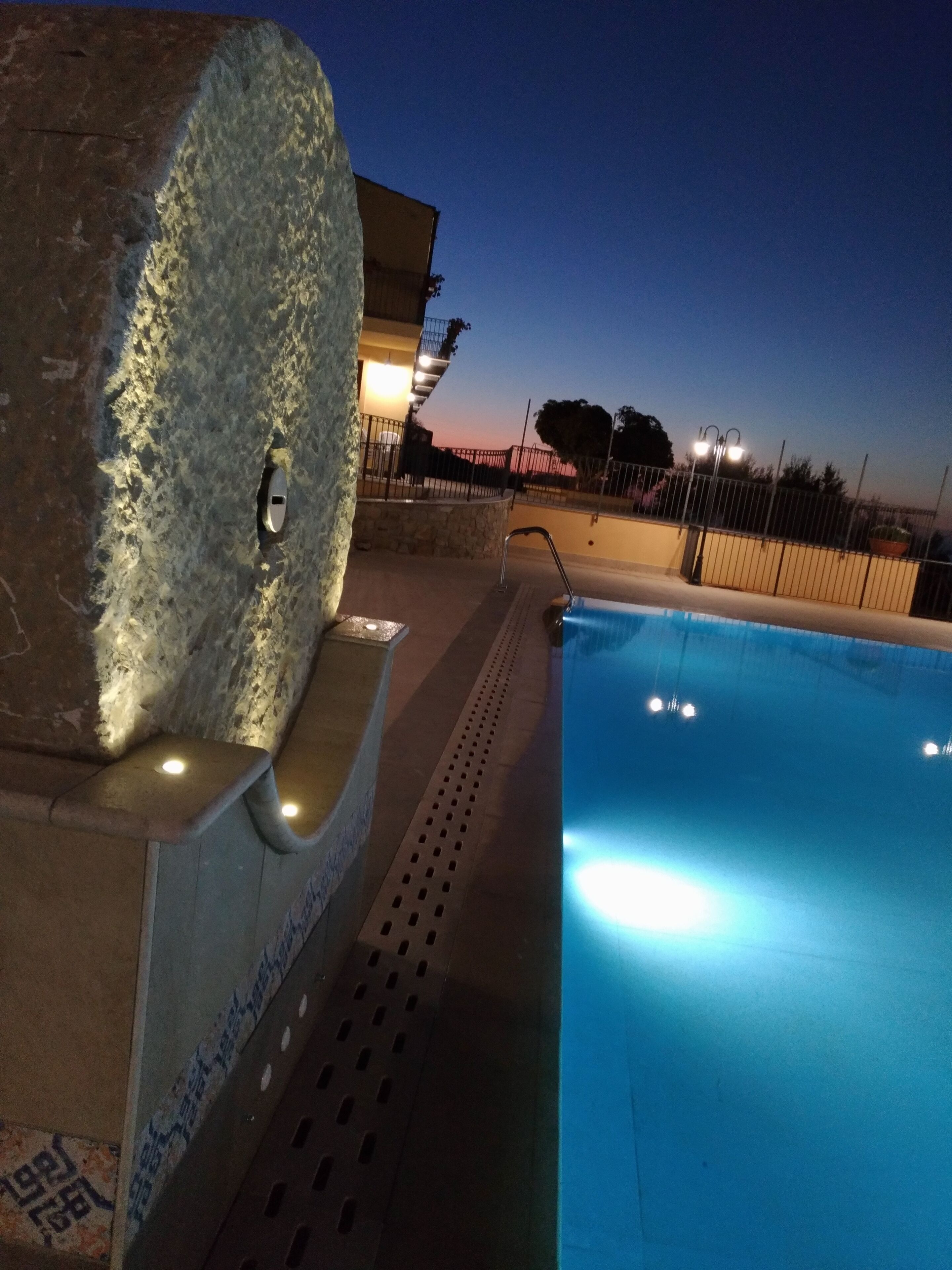 Una piscina con un muro de piedra y una barandilla de metal.