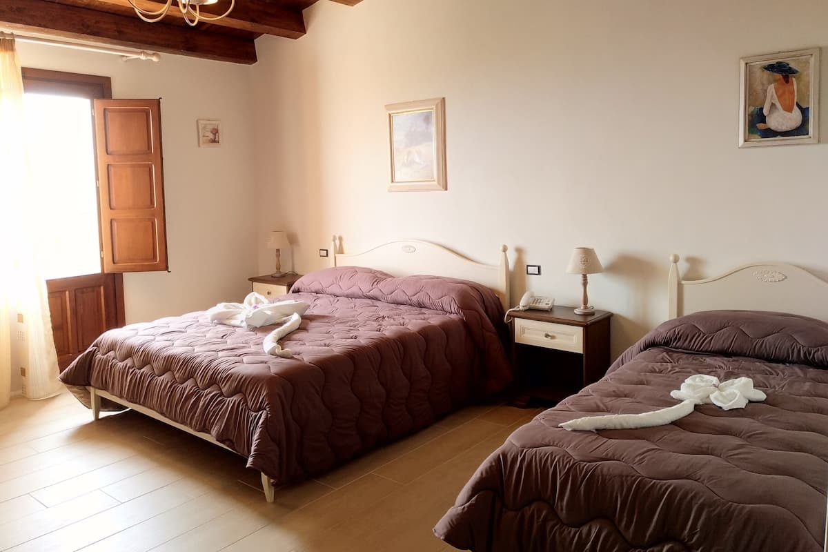 Una habitación de hotel con dos camas, cabeceros de madera, techo de madera y un cuadro en la pared.