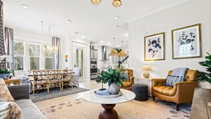 A modern living room with a round coffee table, a sofa, a leather armchair, and a dining area with a wooden table and chairs. - Pet Friendly & A Minute From Prominence Pool, Sleeps 8 (Santa Rosa Beach)