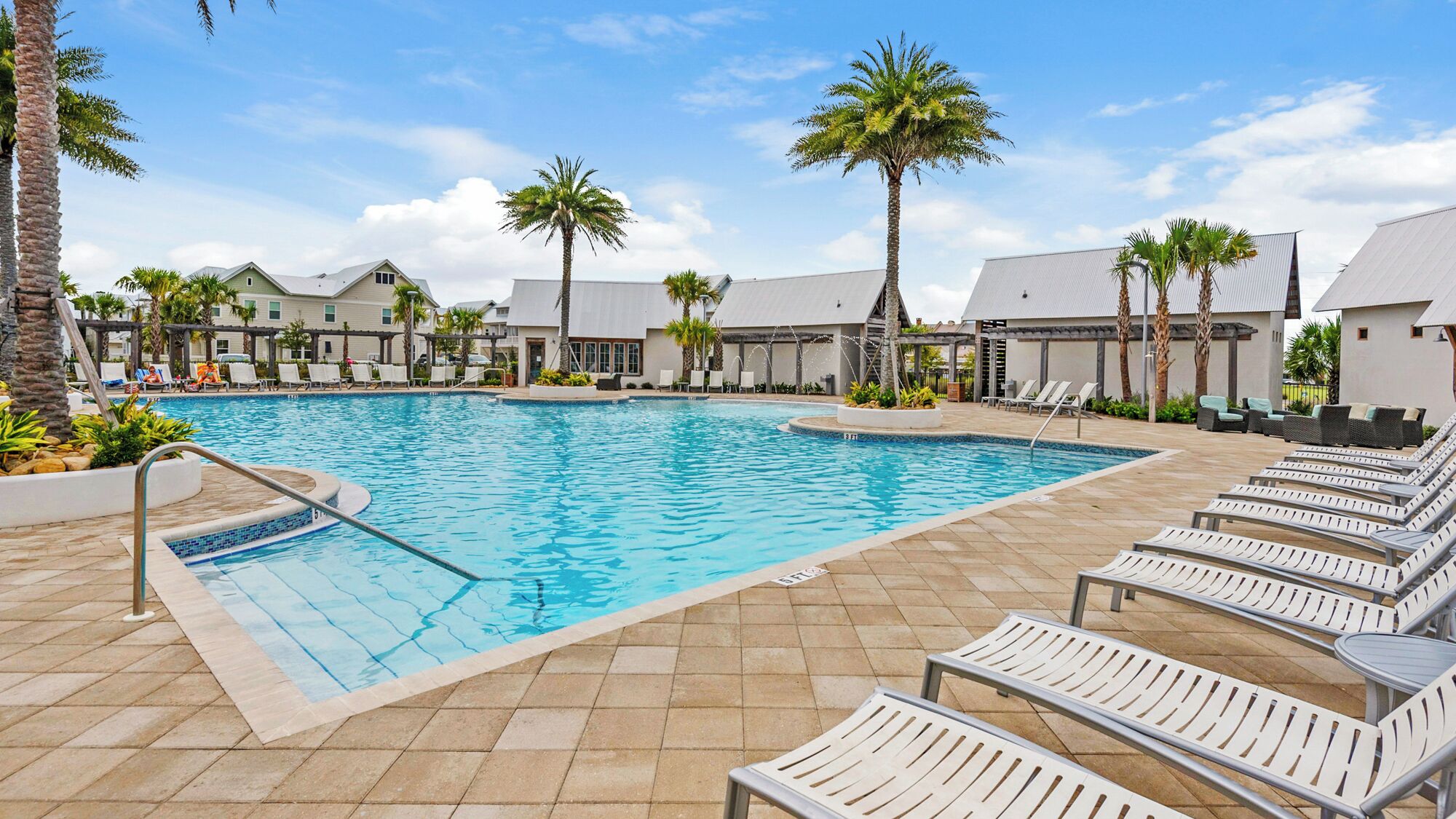 A swimming pool with lounge chairs and palm trees.