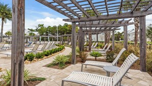 A covered outdoor seating area with multiple lounge chairs and a pergola structure. - Pet Friendly & A Minute From Prominence Pool, Sleeps 8 (Santa Rosa Beach)