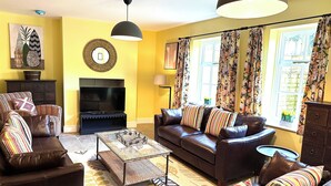A living room with a sofa set, a coffee table, a TV, and a fireplace. - Honey stone and style year round (Winchcombe)