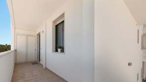 A corridor with white walls, a potted plant, and a door at the end. - Casa di Tosca by BarbarHouse (Torre dell'Orso)