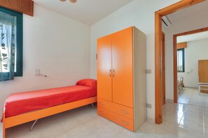 A bedroom with a single bed, an orange wardrobe, and a tiled floor.