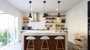 A modern kitchen with a central island, pendant lighting, and a view to the outside.
