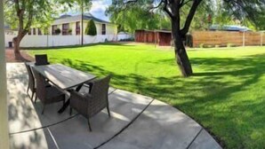 A backyard with a lawn, a table, and chairs.