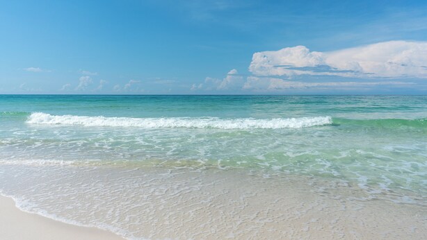 A beach with clear turquoise water and gentle waves. - Pet Friendly + Private Pool; Amazing Fenced Backyard, 5 Min Walk to Beach! (Panama City Beach)