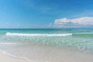 A beach with clear turquoise water and gentle waves. - Pet Friendly + Private Pool; Amazing Fenced Backyard, 5 Min Walk to Beach! (Panama City Beach)