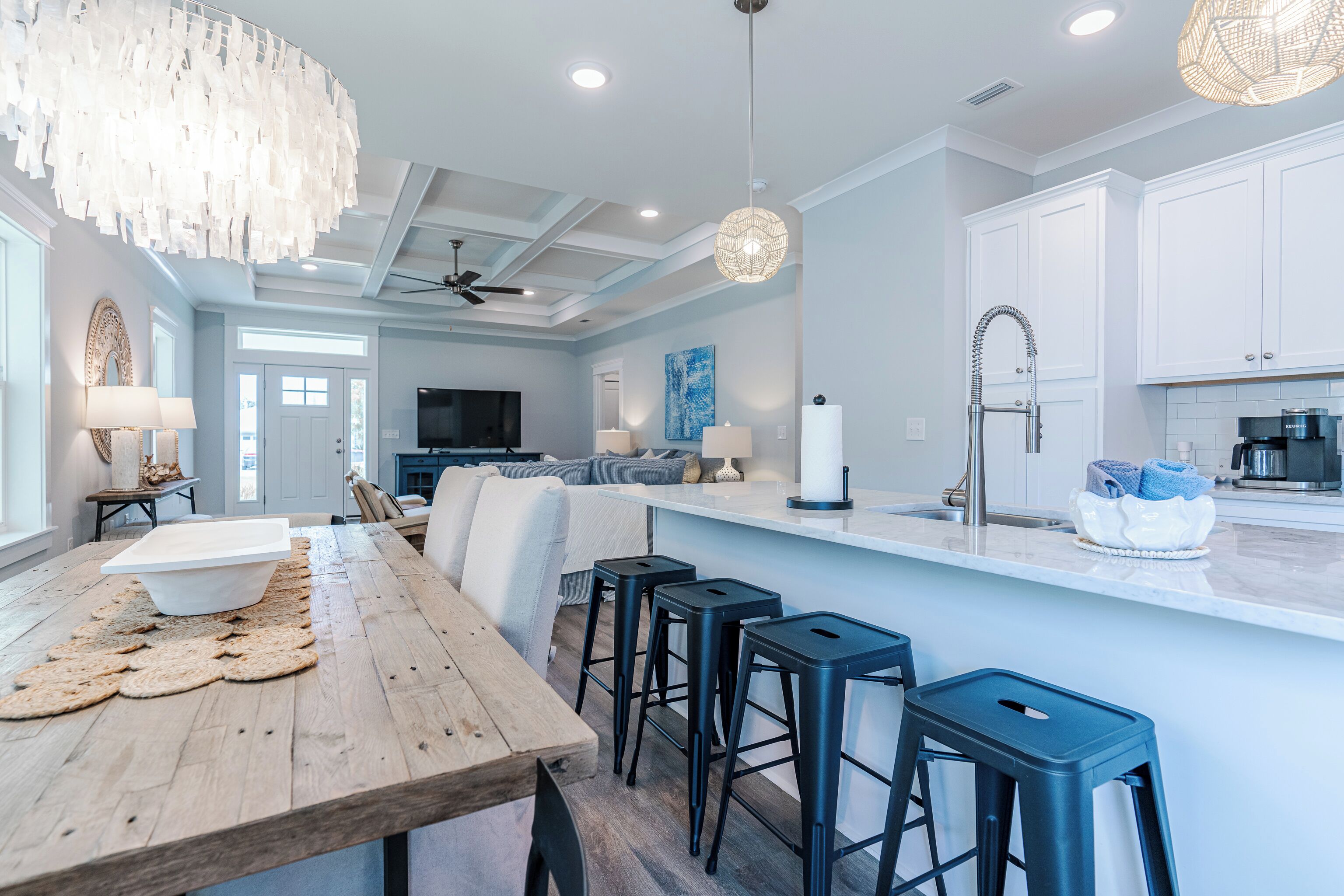 Una cocina moderna con armarios blancos, una mesa de comedor de madera y taburetes negros.