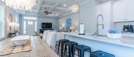 Una cocina moderna con armarios blancos, una mesa de comedor de madera y taburetes negros.