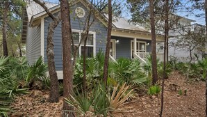 A small, single-story building with a porch, surrounded by various types of trees and plants. - Pet Friendly Beach Home; 2 Minutes to Beach & Eastern Lake (Santa Rosa Beach)