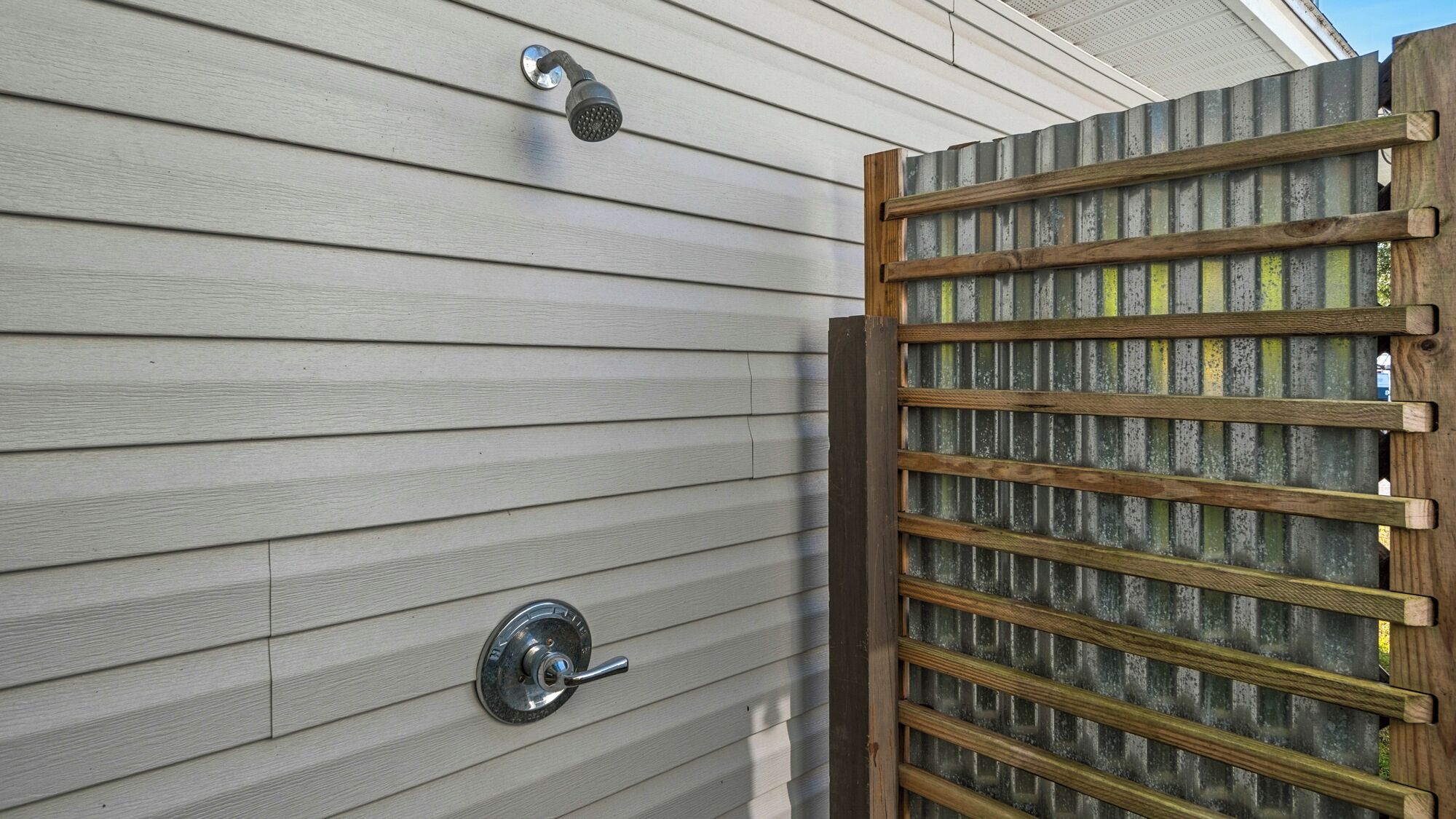A house exterior with siding, a metal door with a handle, and a wooden fence with vertical slats.