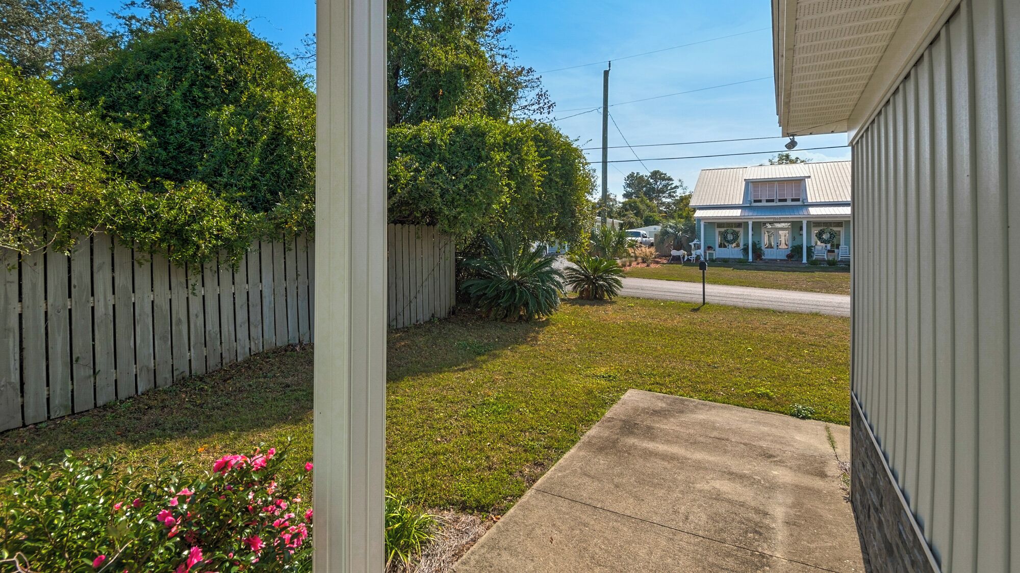 A residential property with a front yard, a wooden fence, and a house with a porch.