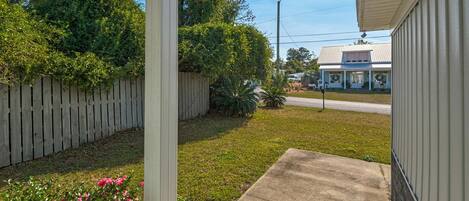 A residential property with a front yard, a wooden fence, and a house with a porch.