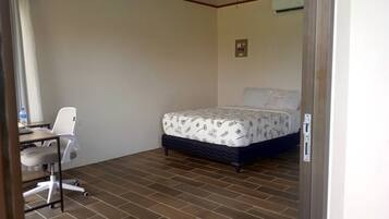 A small, clean room with a bed, a desk, and a chair.