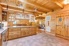 A spacious wooden cabin interior with a large kitchen area, a dining area, and a cozy living room. - Rogers Cabin on 17 Acres w/ Wraparound Deck! (Rogers)