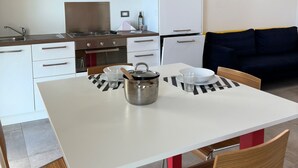 Une cuisine moderne avec des meubles blancs, une cuisinière en acier inoxydable et une table à manger avec des chaises.