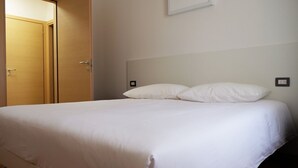Une chambre d’hôtel avec un lit, une porte en bois et un interrupteur sur le mur.