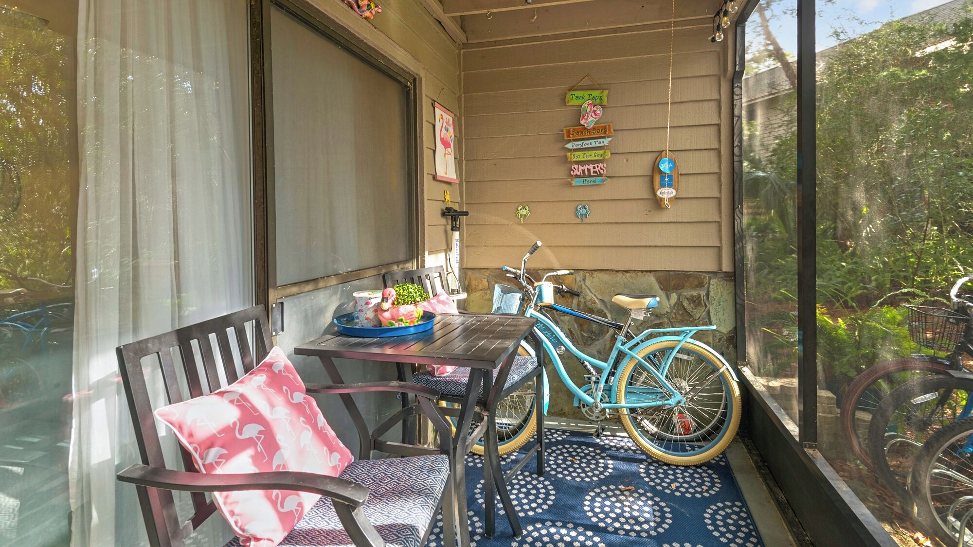 A covered porch with a table, chairs, and a bicycle.