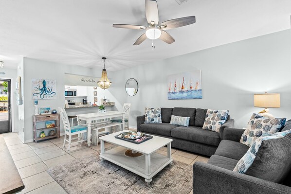 A modern living room with a dining area, a ceiling fan, and a kitchen in the background. - Pool + Tennis & Nature Trails & 6 Minutes to Beach (Santa Rosa Beach)