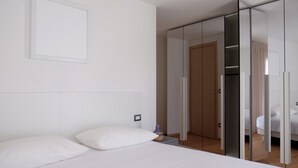 A modern hotel room with a bed, a bedside table, and a wardrobe with a mirror. - Spacious apartment in the heart of the Dolomites (Sospirolo)