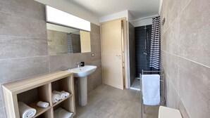 A modern bathroom with a wooden vanity, a white sink, a towel rack, and a shower area. - Spacious apartment in the heart of the Dolomites (Sospirolo)