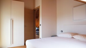 Een slaapkamer met een bed, een kledingkast en een deur naar een andere kamer.
