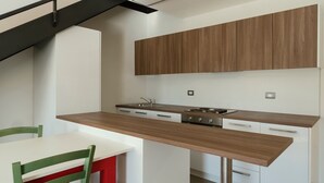 Een moderne keuken met witte kastjes, een houten aanrechtblad en een ingebouwde kookplaat.