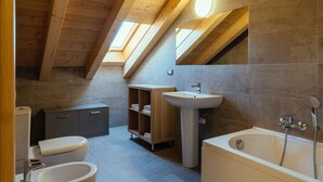 Een moderne badkamer met dakraam, bad, wastafel en toilet.