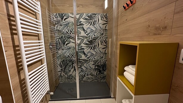 Un baño con ducha, toallero y repisa con toallas.