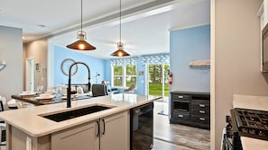 A modern kitchen with a central island, pendant lighting, and a view to the outdoors.