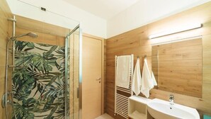Un baño con ducha, lavabo y paneles de madera.