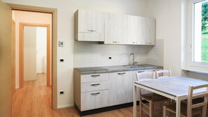 Una cocina moderna con armarios de madera clara, un lavamanos integrado y una zona de comedor con mesa y sillas.