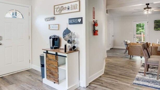 A modern kitchen with a coffee station, a dining area with a table and chairs, and a hallway leading to another room. - Cozy Oasis of Downtown Clarksville (Clarksville)