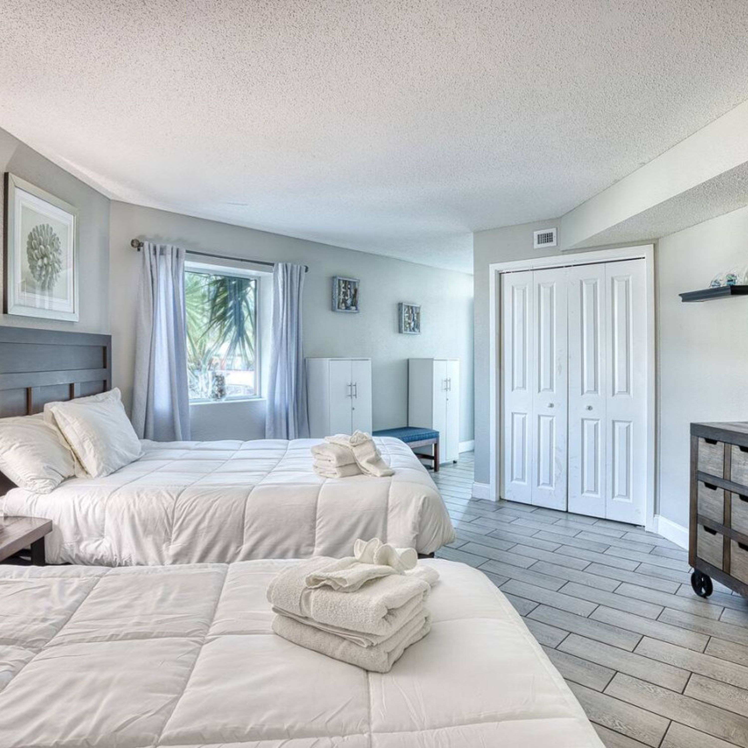A bedroom with two beds, a desk, a chair, and a wardrobe.
