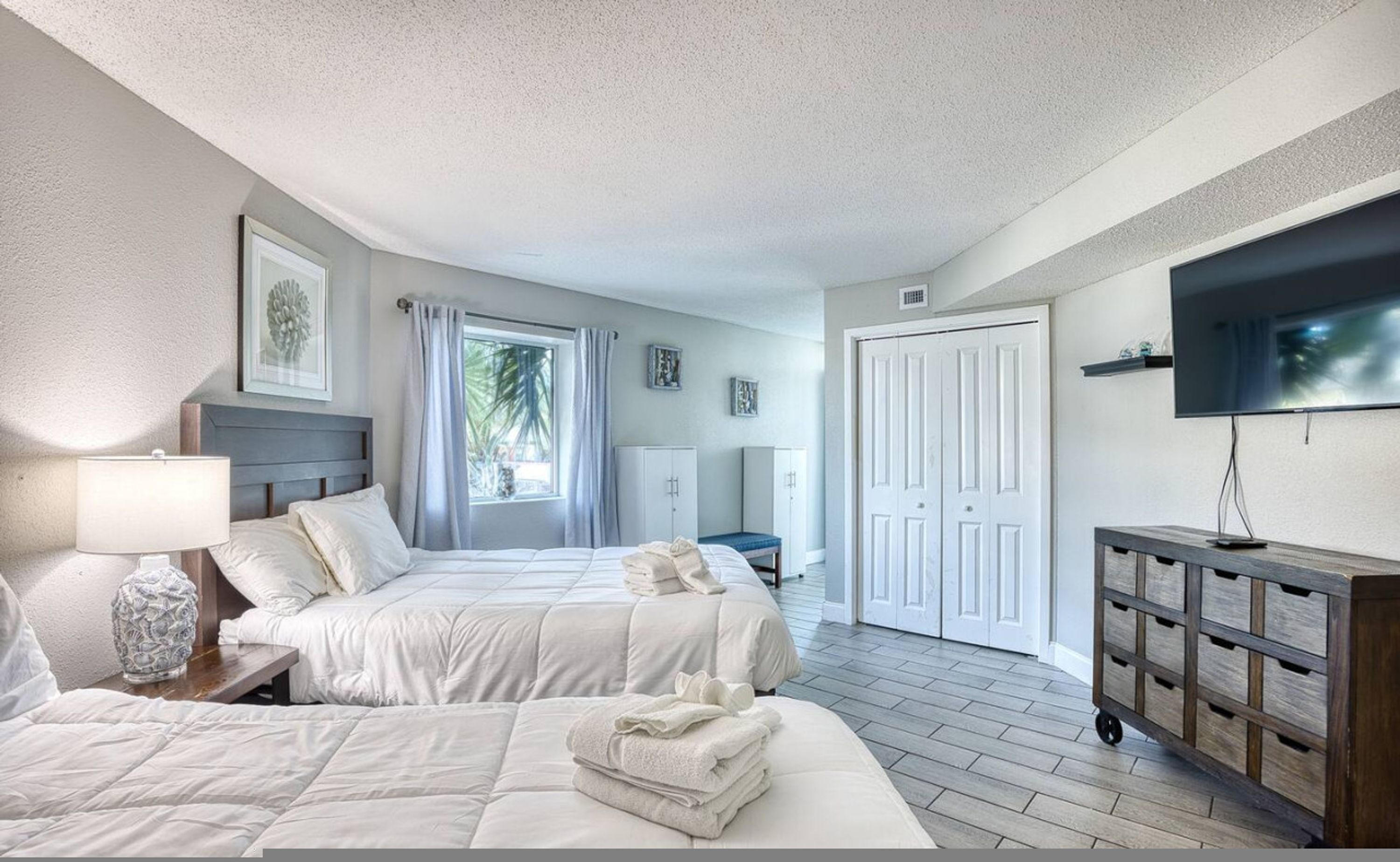A hotel room with two beds, a TV, a desk, and a wardrobe.