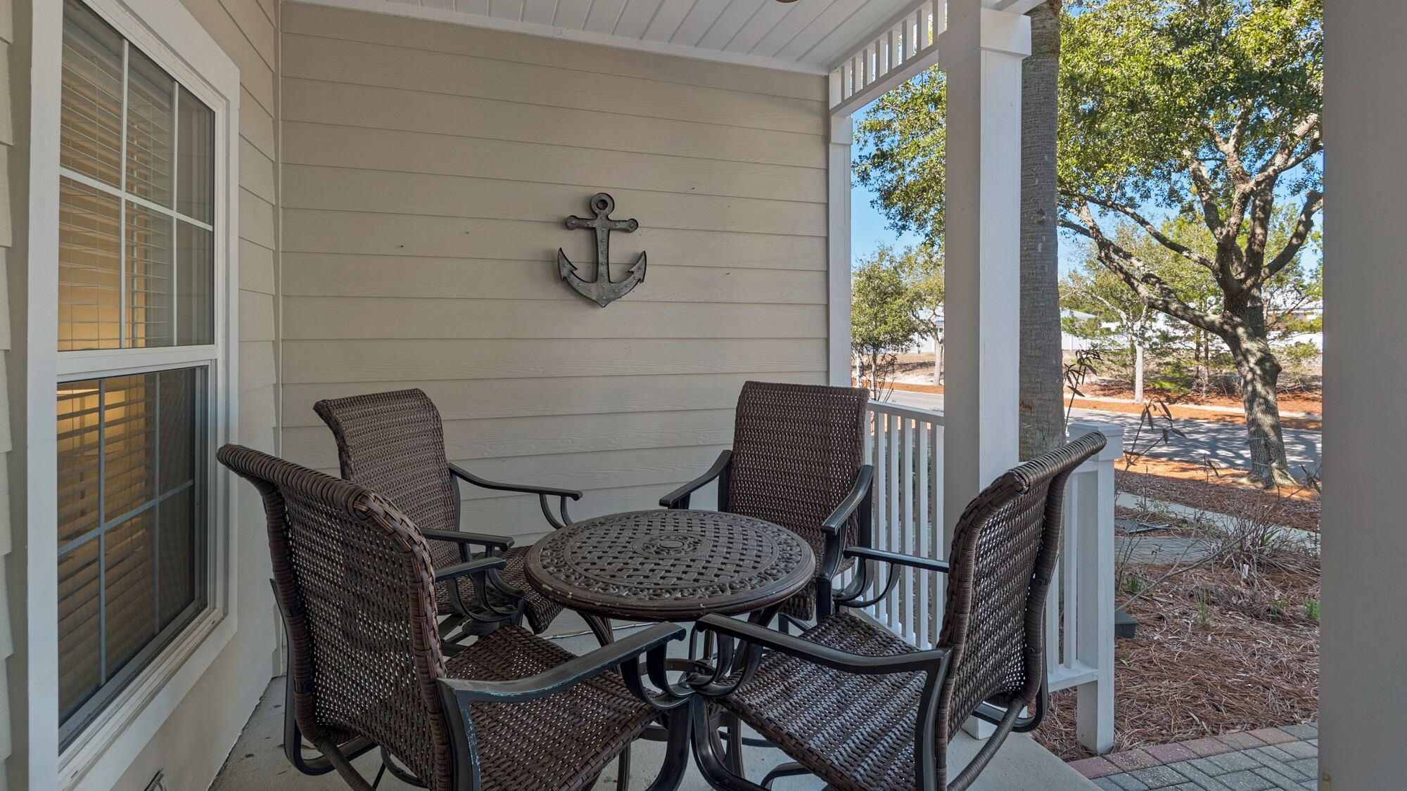 A covered patio with wicker furniture and a decorative anchor on the wall.