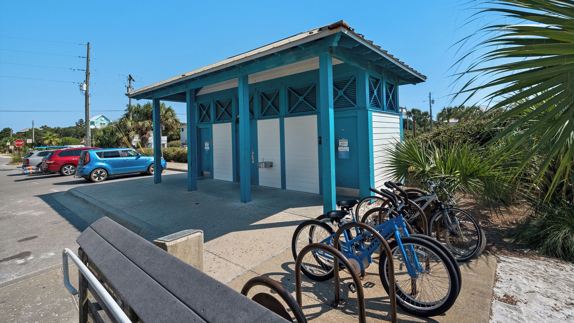 Uma área de estacionamento coberta com um edifício azul e branco, uma placa de parada e várias bicicletas estacionadas.