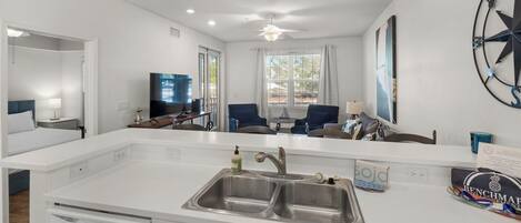 A modern kitchen with a double sink, a dishwasher, and a dining area with a table and chairs.