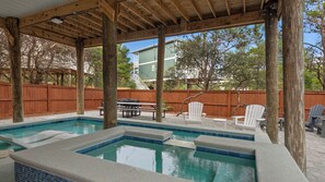 Piscina descoberta coberta com um deck de madeira, cerca de madeira e mobiliário de exterior.