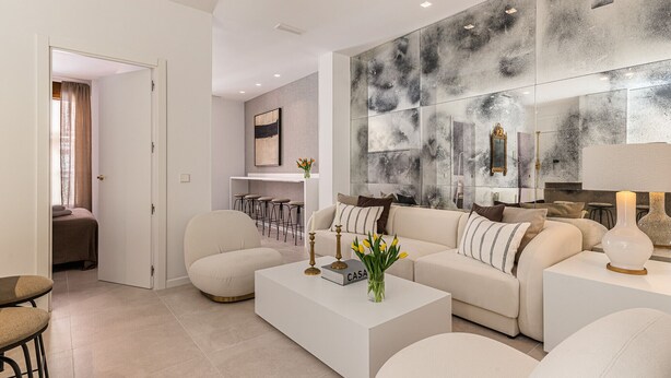 A modern living room with a sofa, coffee table, and bar stools.